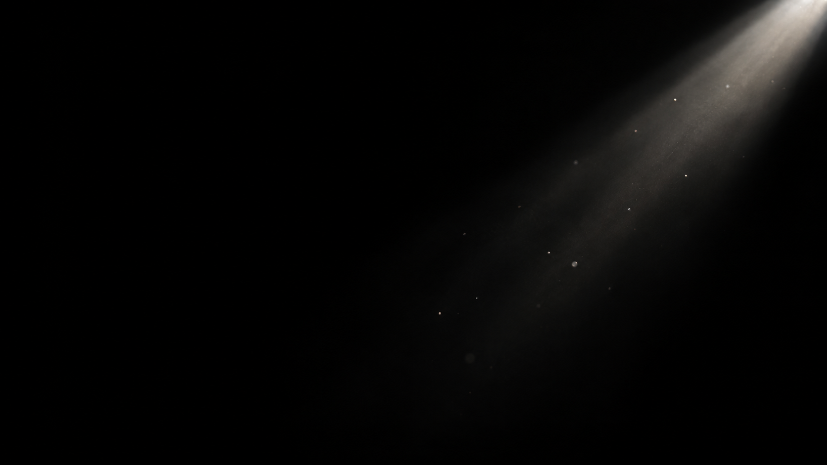 A narrow white shaft of light enters diagonally from a small unseen aperture at the upper right, revealing just a dozen tiny dust motes on black.