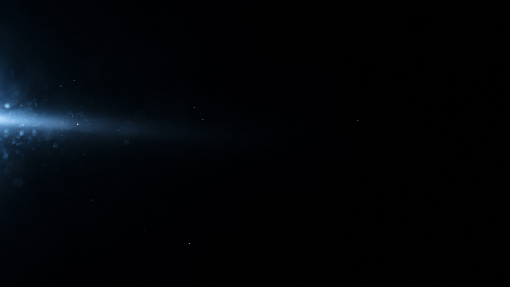 A subtle cold blue beam enters horizontally from the left edge and dissipates quickly into black, a few pinprick silver particles.