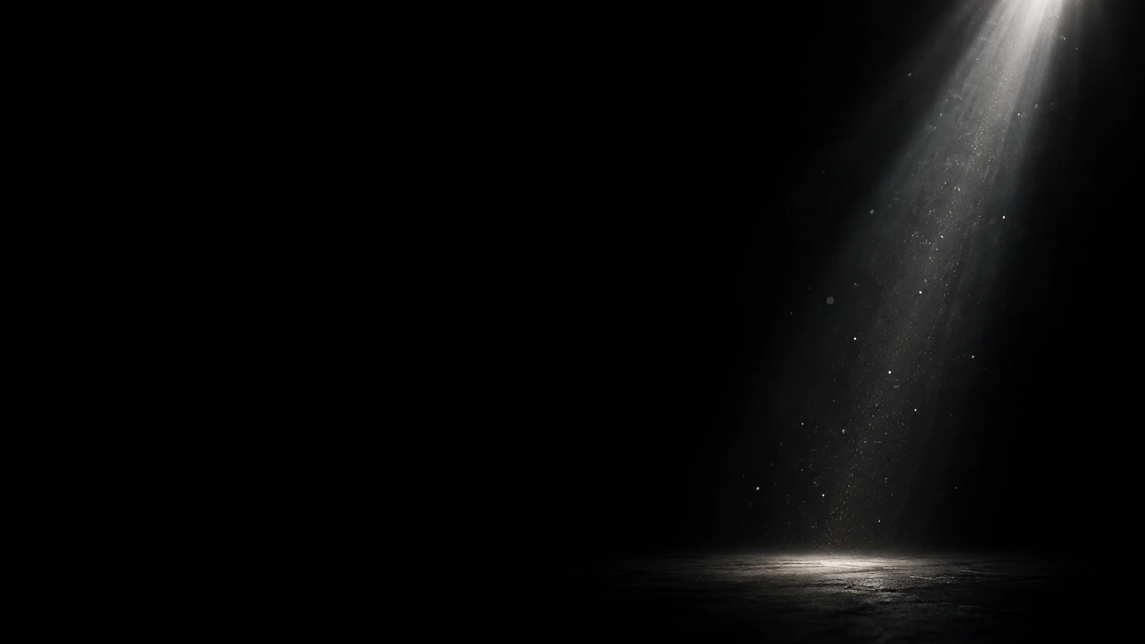 A narrow column of silver light falls from the top right through sparse tiny falling dust, almost all frame black.