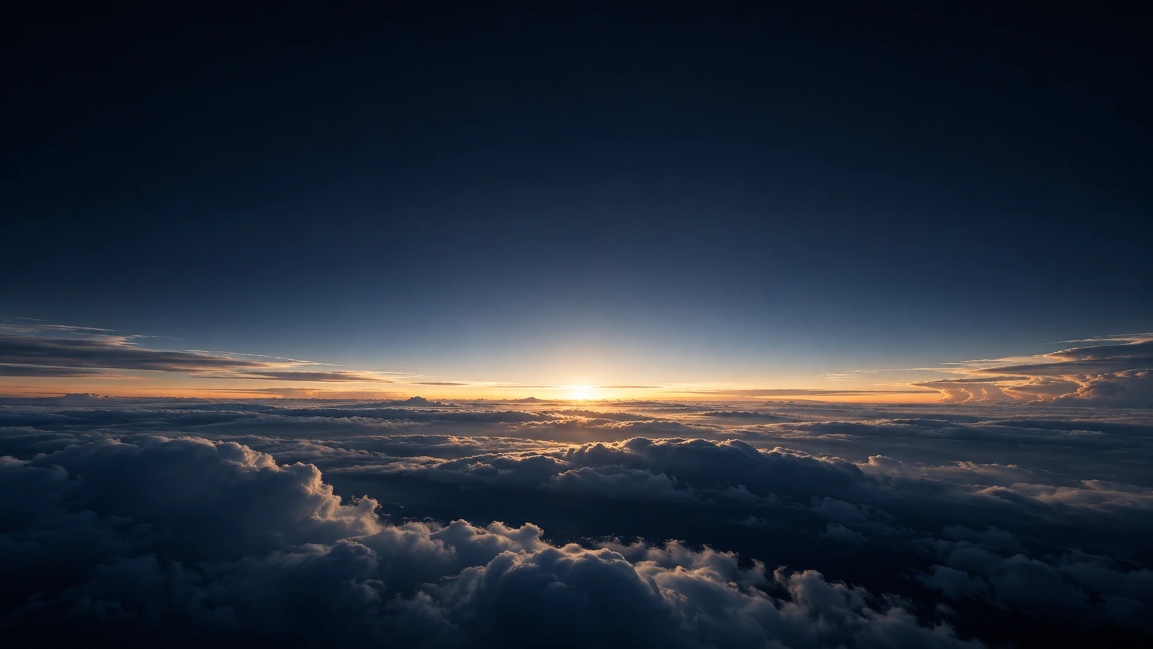 A thin white-gold dawn line illuminates the top of low dense clouds beneath a vast nearly black upper atmosphere.