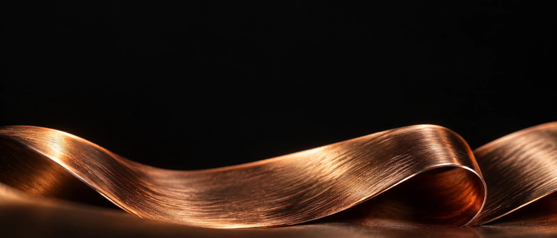 Panoramic macro of a narrow folded strip of brushed copper along the lower edge, microscopic brushed grain and realistic warm specular highlights on black.