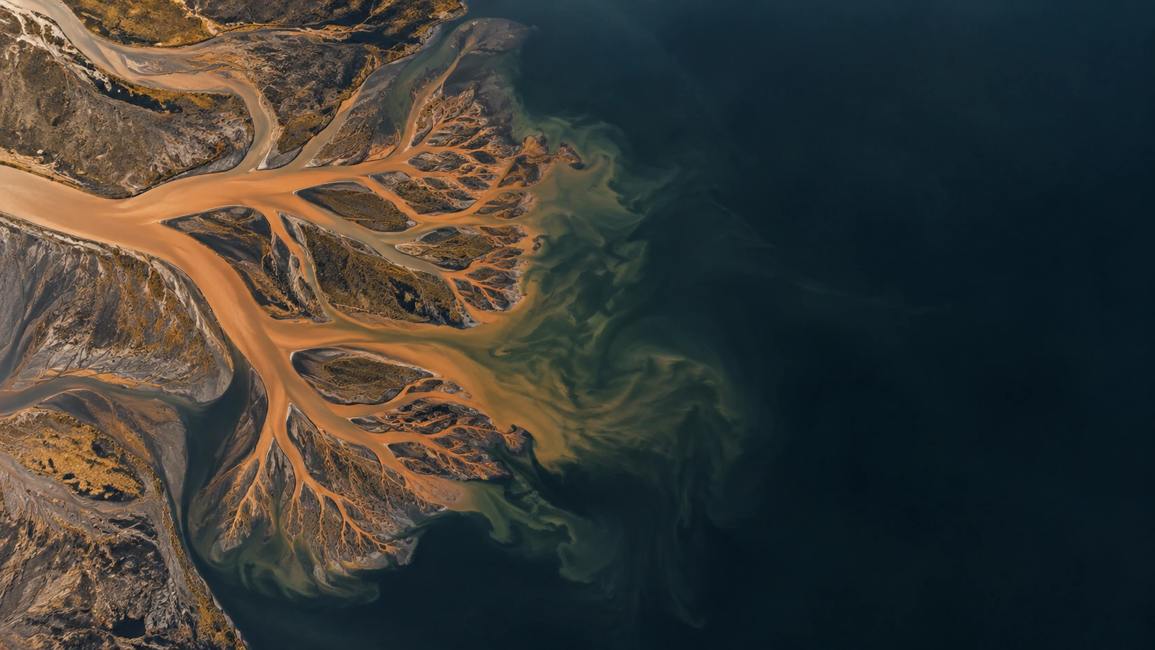 A natural copper-colored river delta fans into a dark mineral lake, intricate channels with quiet dark water around.