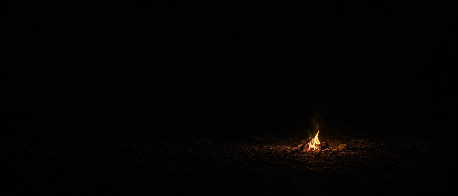 A small irregular campfire burns on dark earth, with broad black space above and to the left.