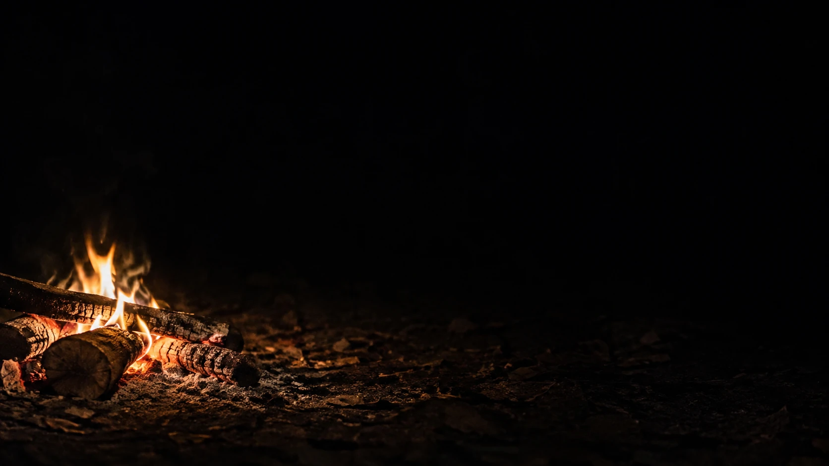 A low campfire on the far left illuminates a small patch of rough earth.