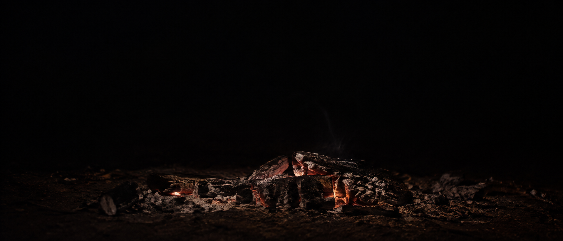 A thin bed of fading coals stretches along the lower edge of an almost black frame.