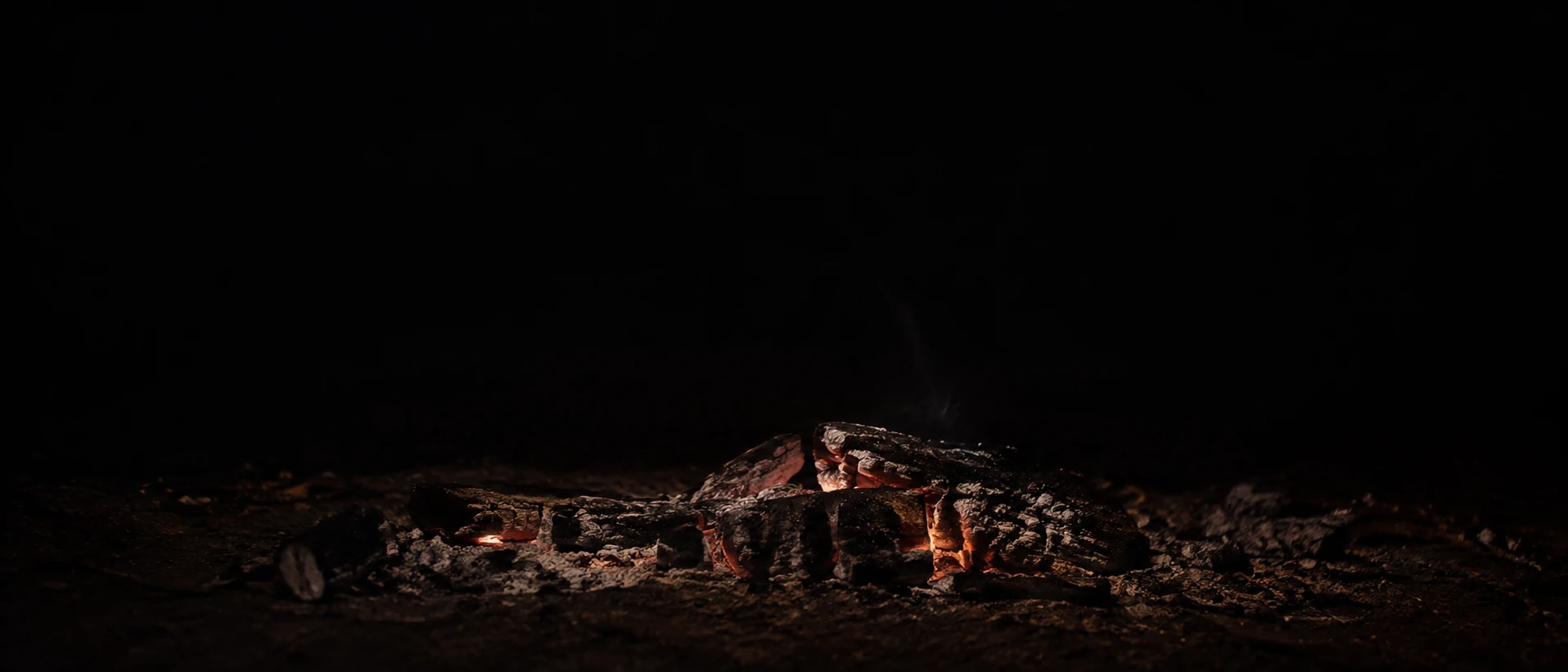 A thin bed of fading coals stretches along the lower edge of an almost black frame.