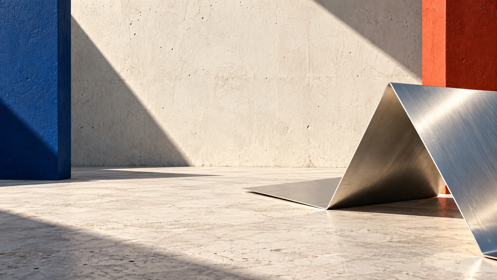 One sharply folded sheet of brushed aluminum rests on pale concrete, its reflective edges forming a spare architectural zigzag.