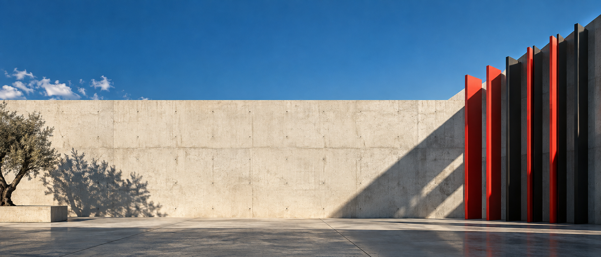 A panoramic pale concrete wall with a sequence of narrow red and black vertical fins clustered at one end, directional afternoon light.