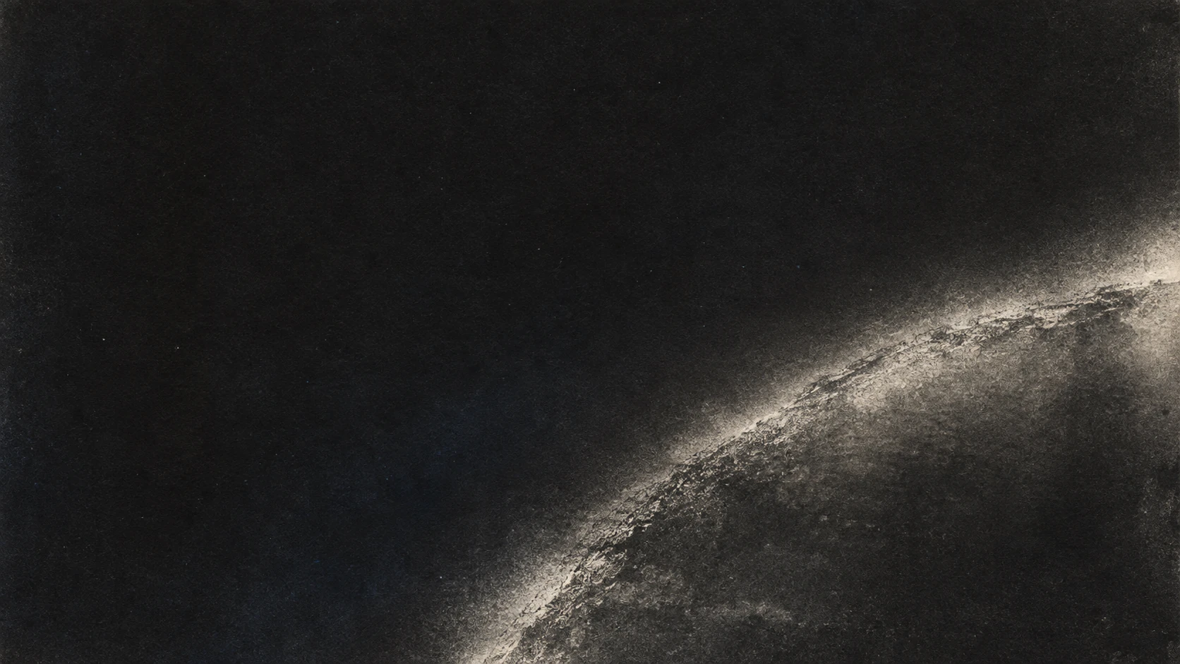 An irregular silver exposure arc crossing finely grained charcoal photographic paper.