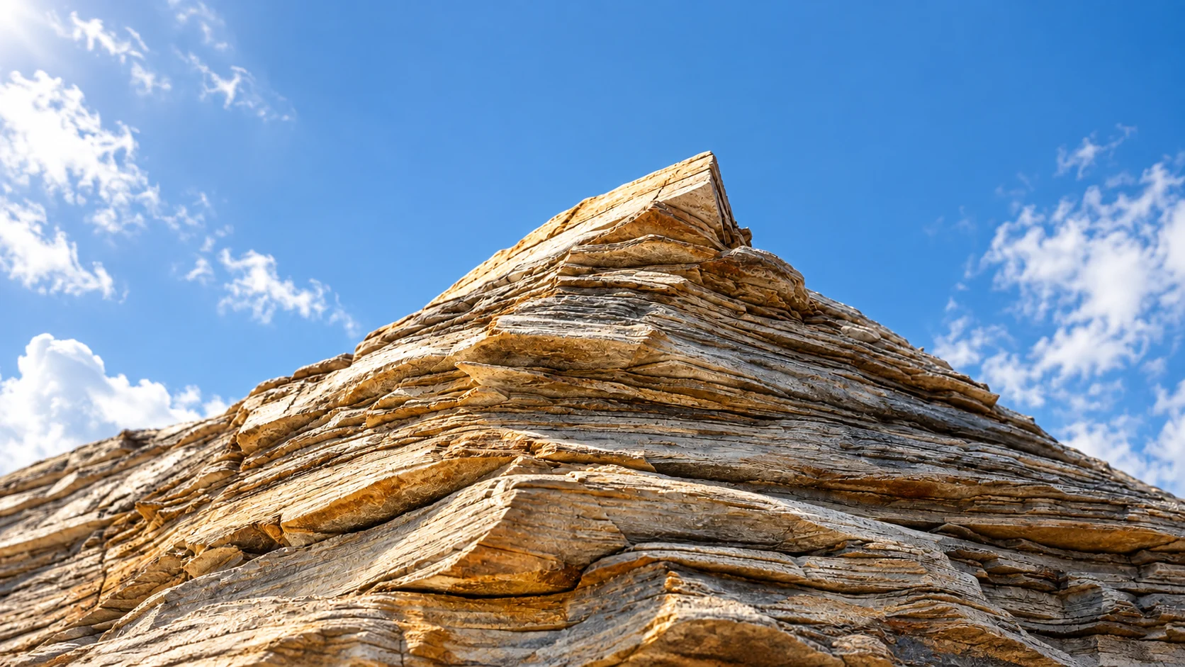 A close view of a layered sculptural stone peak in clear natural daylight.
