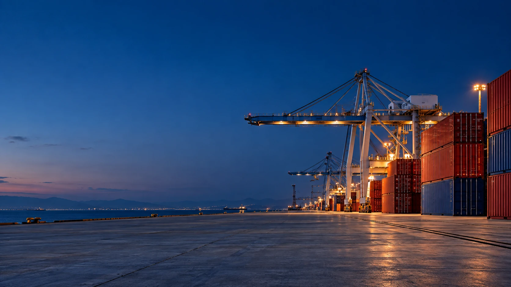 Blue-hour terminal, restrained warm service lights on right behind red container stacks, huge clean navy sky and concrete foreground on left, cinematic yet realistic.