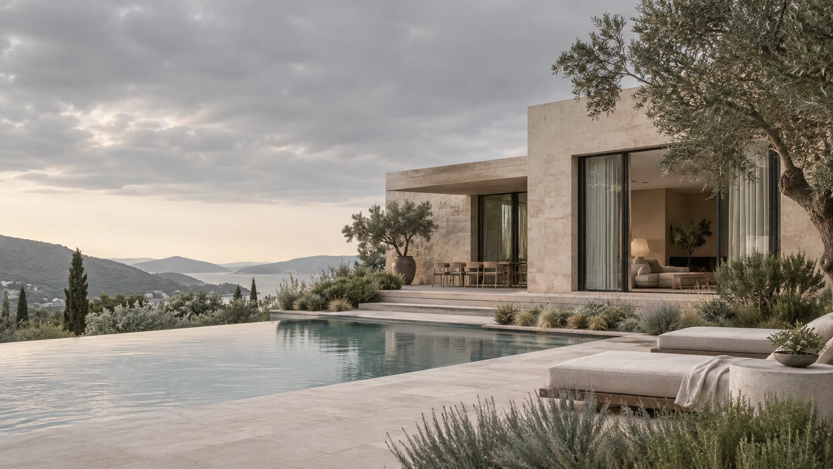 Modern residence in pale blush limestone beneath overcast sky, garden beds with soft grasses, sage-green glazing reflections, serene distinctive cooler color treatment.