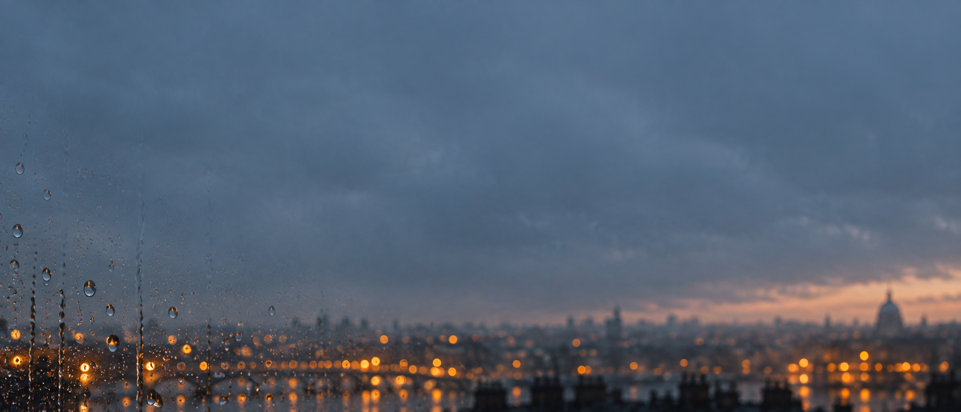 Rain-streaked glass and soft city light. Quiet divider or quote background.